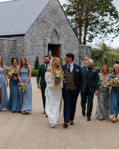 Couple stroll with wedding party at irish country estate wedding venue